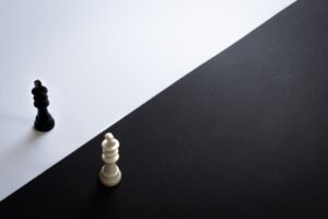 Black chess piece on a white background, and a white chess piece on a black background